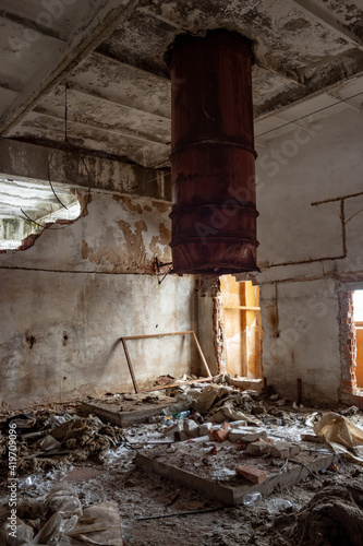 A large rusty pipe sticks out of the ceiling in the ruins of a former