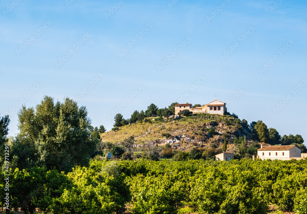 Small church of San Miquel, on a small hill surrounded by orange groves and country houses, in La Font d'En Carròs (Valencia, Spain)
