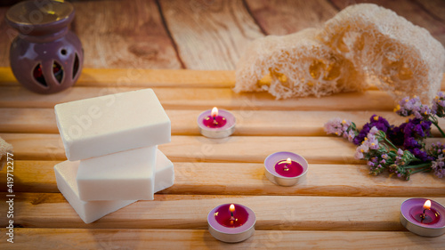Beautiful spa composition with natural soaps with scented candles and bathroom accessories in a romantic setting for a cleansing concept. There is shallow depth of field and room for text.