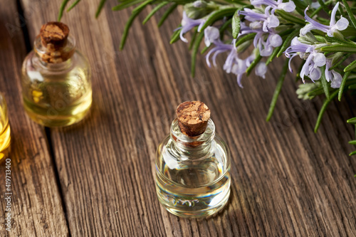 Essential oil bottles with blooming rosemary plant