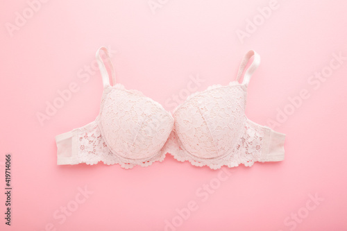Lace bra on light pink table background. Pastel color. Closeup. Daily female underwear. Top down view.