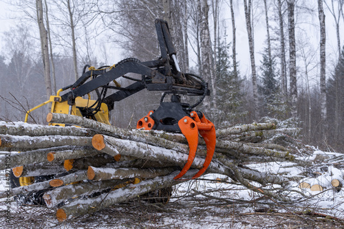 small stand-on mini skid steer with grapple full of wooden logs