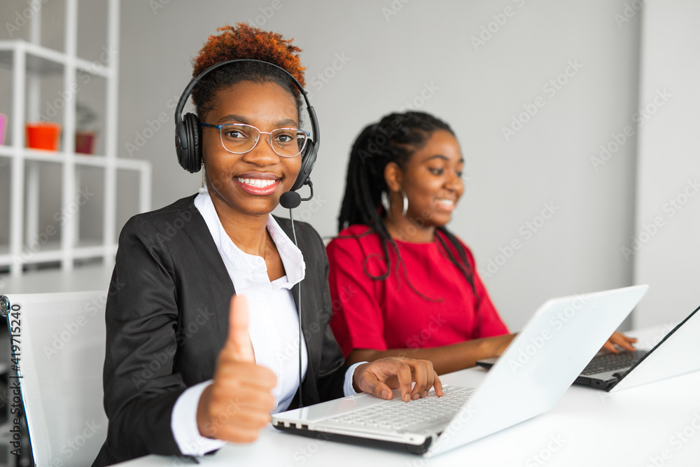 two beautiful african young women in the office at the table with a laptop two beautiful african young women in the office at the table with a laptop