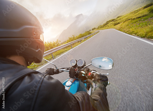 Motorcycle driver riding on mountain highway, handlebars view, Dolomites, central Europe. photo