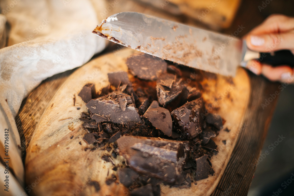 Cut chocolate pieces on a wooden dashboard. Rustic style. Home cooking.