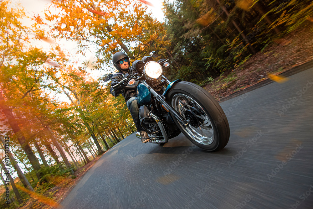 Moto racer riding on forest road during sunset, blurred motion.