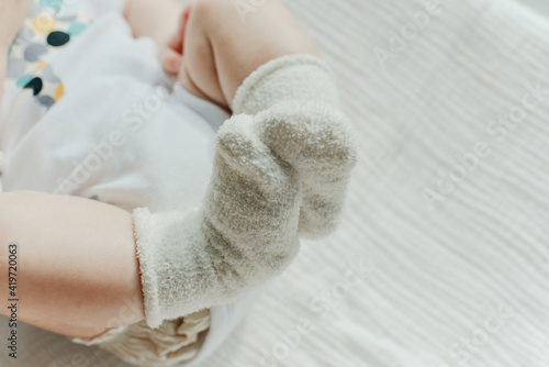 Baby legs. Crawling baby in white socks and bodysuit. View from above. photo