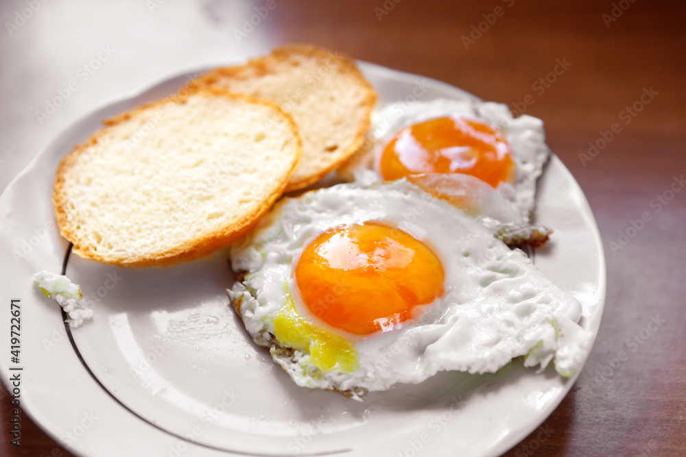 An omelet of chicken eggs, freshly made, is on a plate and two slices of white bread. An omelet of chicken eggs, freshly made, is on a plate and two slices of white bread.