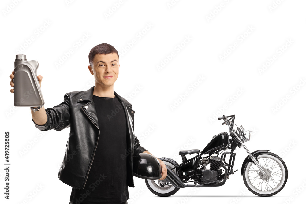 Young man with a chopper holding an engine oil and a helmet Young man with a chopper holding an engine oil and a helmet
