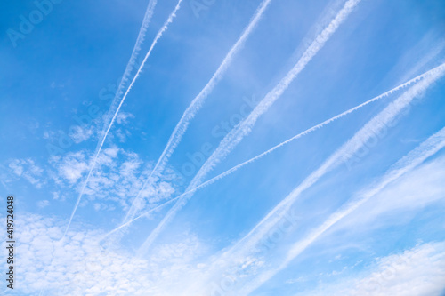 Blue sky with airplane trails and clouds. © Dmitrii Potashkin