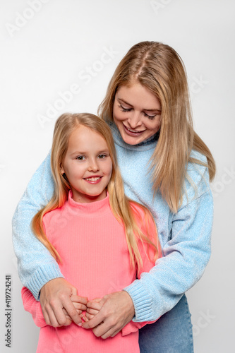 Shot of a happy cheerful mom hugging her little daughter with love against white basckground