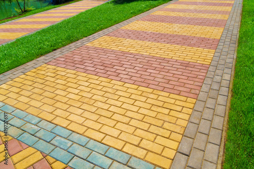 walkway made of paving slabs and green grass as a background, bright sunlight