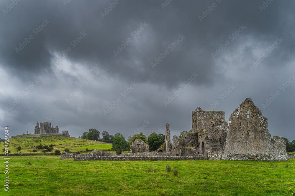 Old ruins of Hore Abbey and Rock of Cashel castle with dark dramatic storm sky in the background, County Tipperary, Ireland