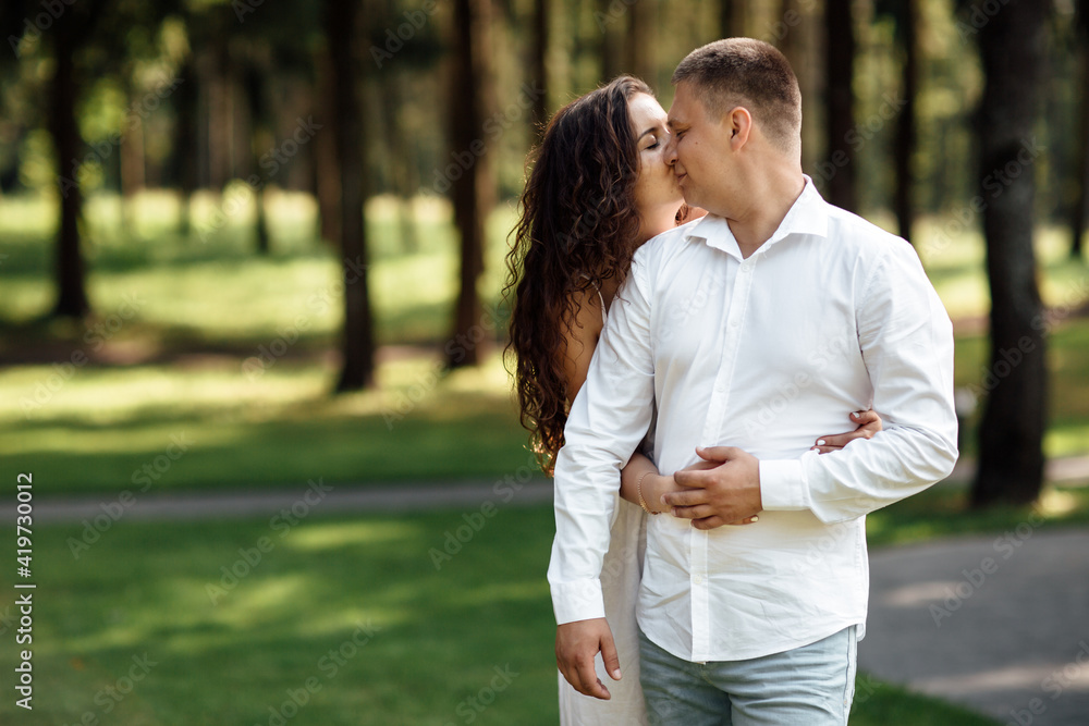 young couple in love is kissing in the park on a summer day. man and woman are hugging outdoors young couple in love is kissing in the park on a summer day. man and woman are hugging outdoors