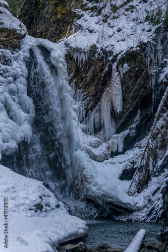 Waterfall, river with rapids and cold winter mountain landscape