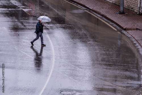 Businessman in a very heavy rain walks down the street.