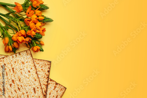 Matzo and flowers on yllow background, top view. Passover (Pesach) Seder Pesah celebration concept (jewish Passover holiday). photo