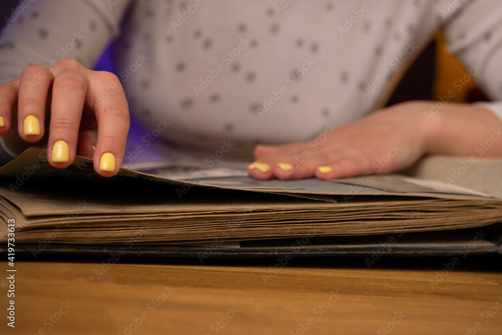 Woman looks through an family album with old photos at table at home.