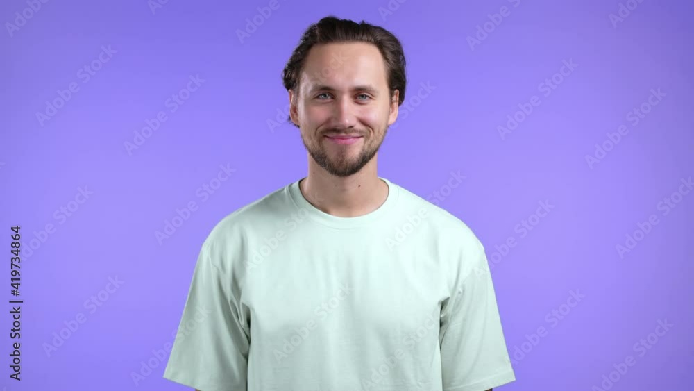 Portrait of cheerful european man looking to camera.Young handsome kind guy smiling in studio on violet background. Portrait of cheerful european man looking to camera.Young handsome kind guy smiling in studio on violet background.
