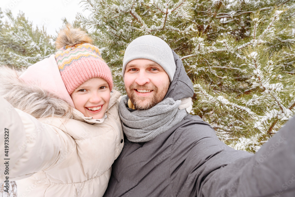 Smiling father and daughter against trees in forest during winter Smiling father and daughter against trees in forest during winter