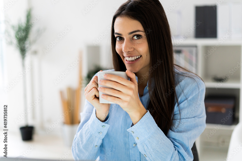 Smiling businesswoman drinking coffee while sitting at office Smiling businesswoman drinking coffee while sitting at office