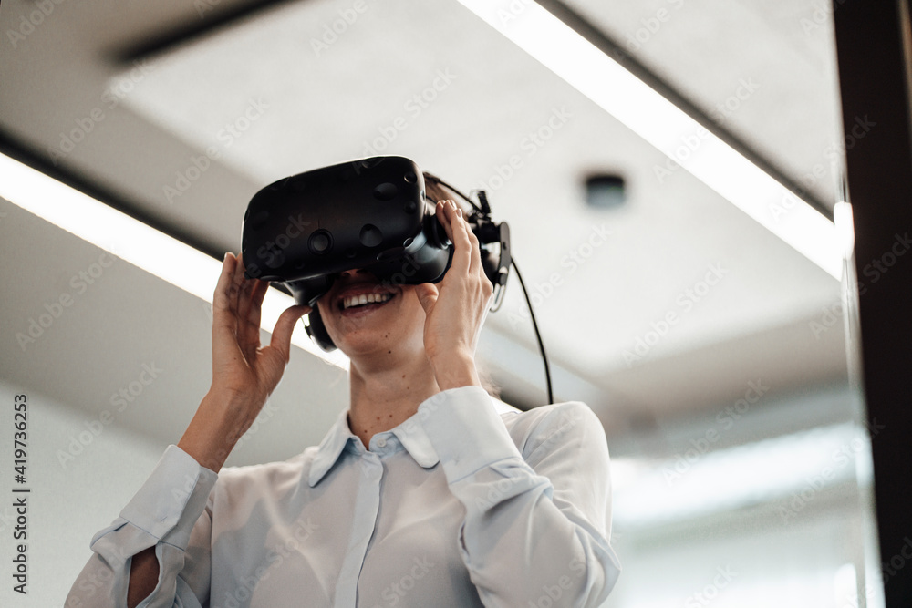 Smiling female entrepreneur wearing virtual reality simulator at office Smiling female entrepreneur wearing virtual reality simulator at office