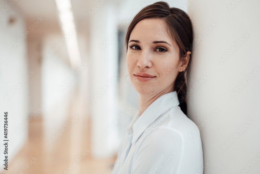 Smiling female entrepreneur against wall in office Smiling female entrepreneur against wall in office