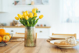 Yellow tulips in a vase on the table. Spring holiday, Easter, home decor.