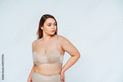 Confident woman in lingerie looking away while standing with hand on hip in studio photo