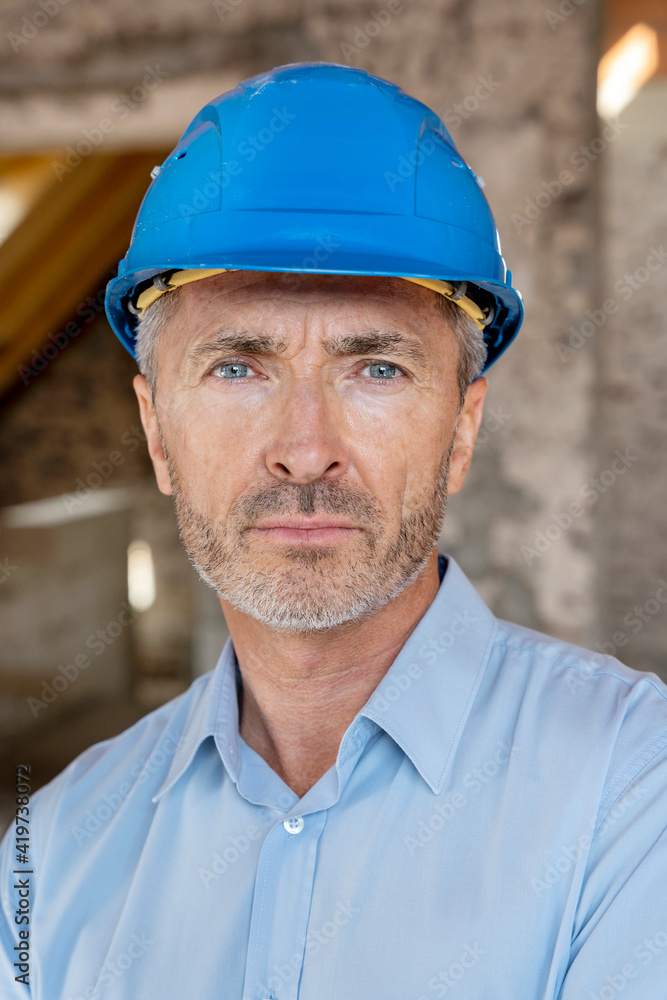 Architect wearing hardhat staring while standing at construction site Architect wearing hardhat staring while standing at construction site
