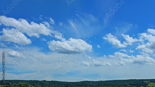 Beautiful cloudscape over a wooded hilly countryside in fine summer day