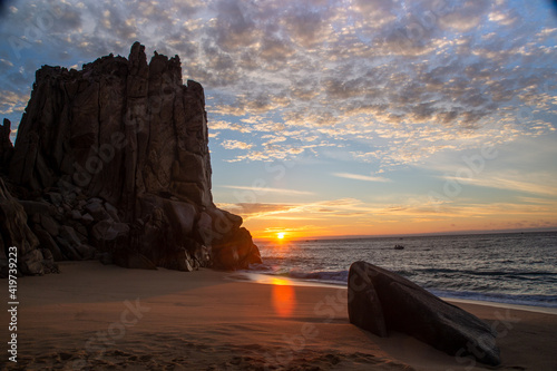 Golden sunrise on the Sea of Cortez by giant rock formations on the sandy beach.