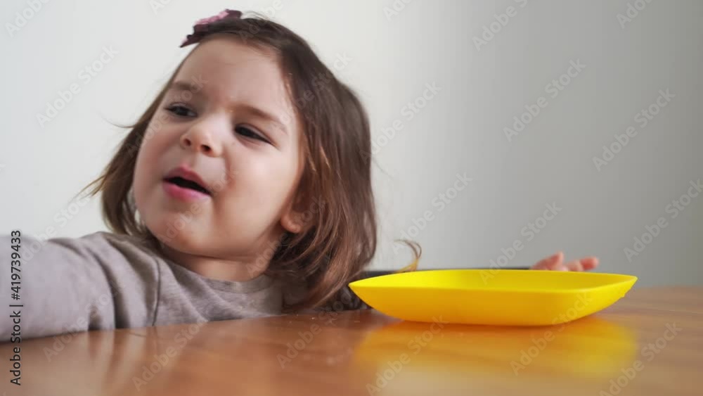 Toddler girl eating bread or pie at home with her hands. Hungry kid. Unhealthy diet. Bad table manners Toddler girl eating bread or pie at home with her hands. Hungry kid. Unhealthy diet. Bad table manners