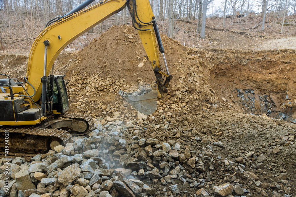 Excavator clearing rock and soil for new road construction site Excavator clearing rock and soil for new road construction site