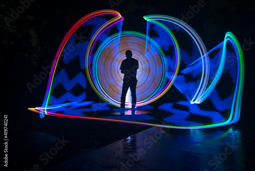 One person standing alone against a Colourful circle light painting as the backdrop © nafi