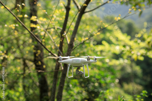 White drone with camera flying in spring tropical forest