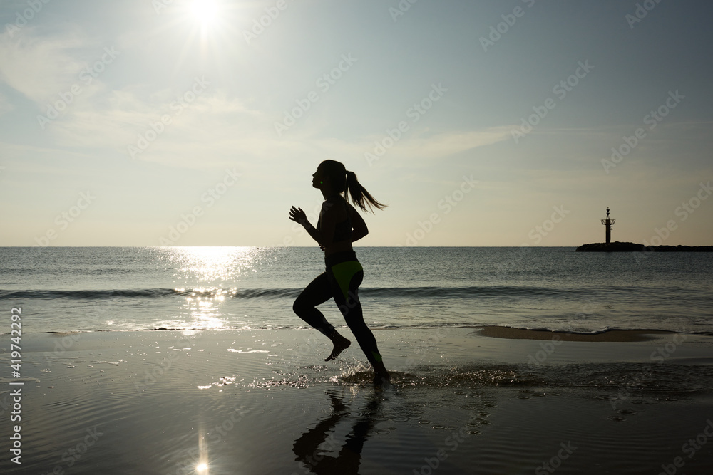Sportswoman running along beach Sportswoman running along beach