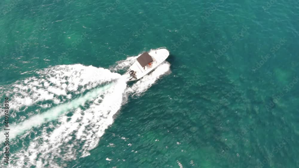 Rotating aerial tracks boat motoring over reef in clear Mediterranean Rotating aerial tracks boat motoring over reef in clear Mediterranean