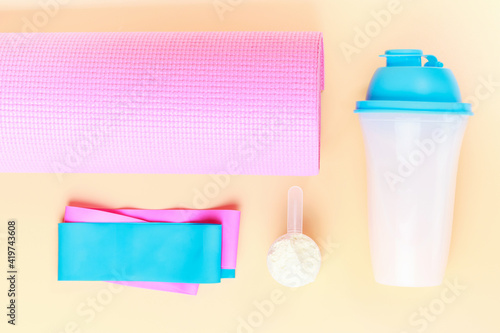Sports accessories and protein shake on brown background close-up, top view