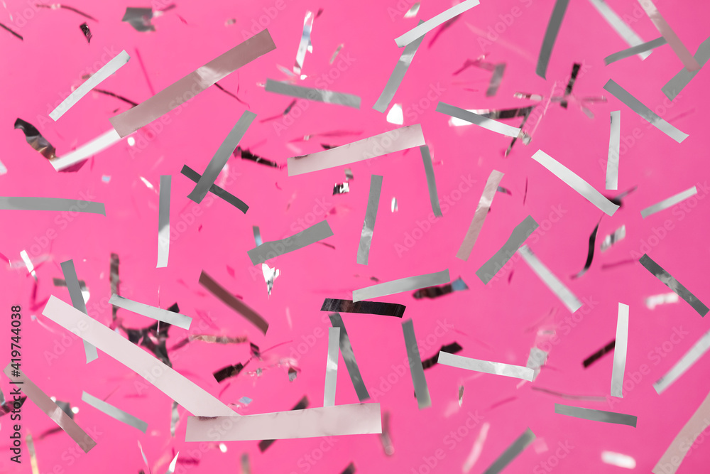 Shiny silver confetti falling down on pink background Shiny silver confetti falling down on pink background