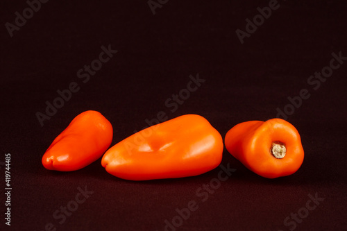 Three orange bell peppers in dark brown background. Small size or tiny.