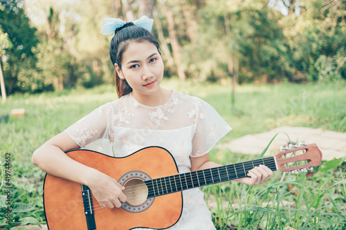 Girl playing guitar in the forest. Music hobby and picnic concept.