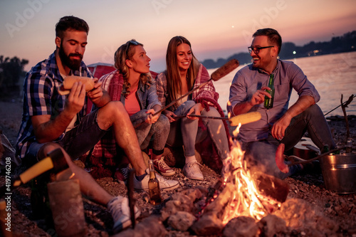 Friends make hot dogs while camping