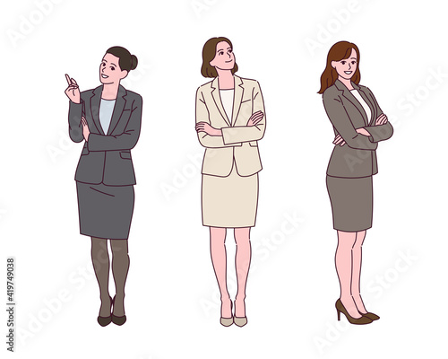 A business woman in a suit is standing with a confident expression.