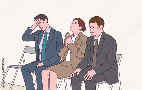 People in suits are praying while waiting for the interview with nervous expressions.