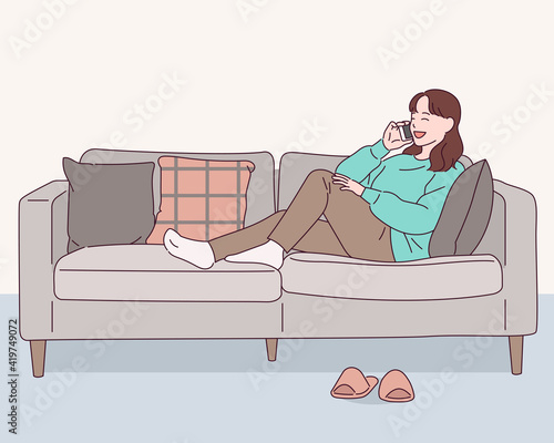 A girl is sitting comfortably on the sofa and talking on the phone.