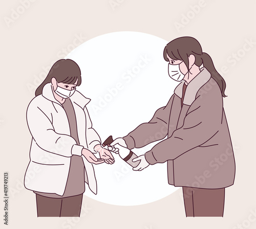 A woman is handing out disinfectant to another.