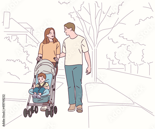 Mom and Dad are walking down the street pushing a stroller.
