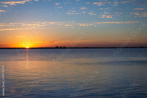 Shocking sunset on the river. The sun sets on the horizon in shades of orange.