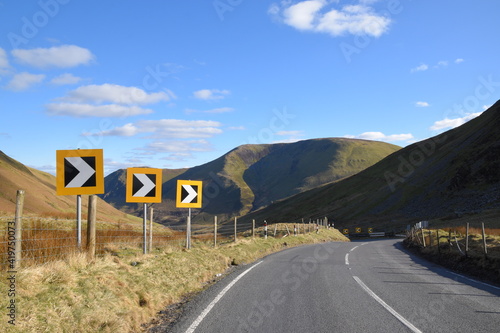 a sharp corner with warning signs on a welsh mountain road